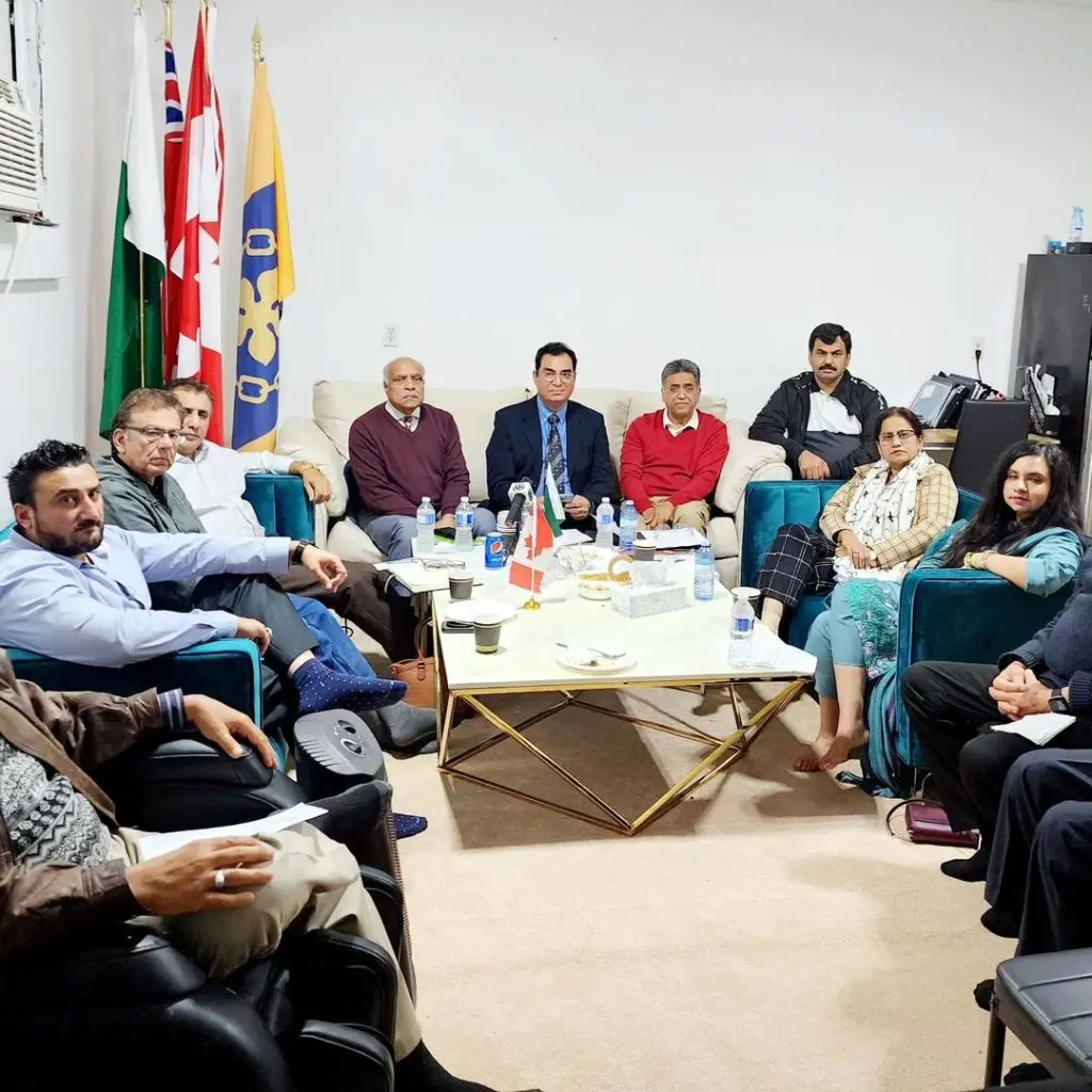 Board and advisory members in a meeting room under a row of flags